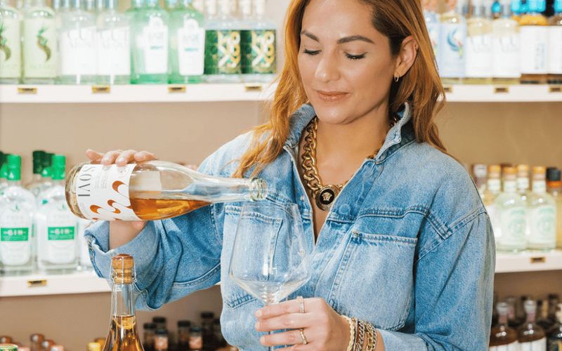 Mehrnush Saadat pouring a bottle of non-alcoholic wine into a glass.
